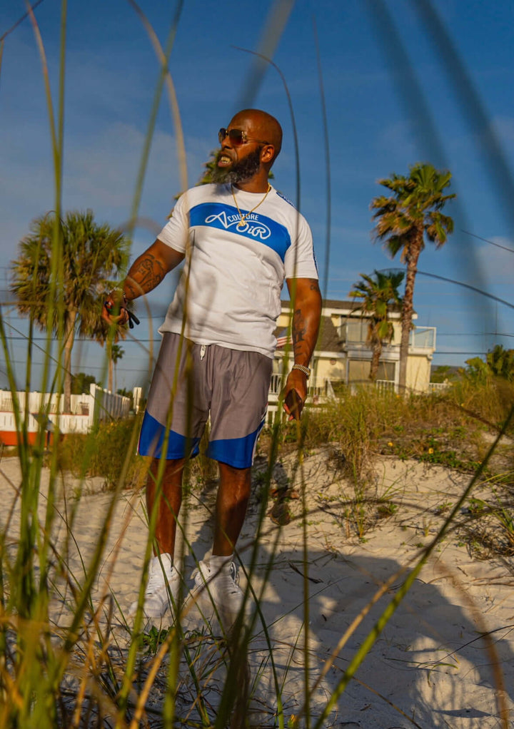 Man wearing Street League Shorts by Avoir – Premium Athletic Streetwear, standing on the beach with palm trees.