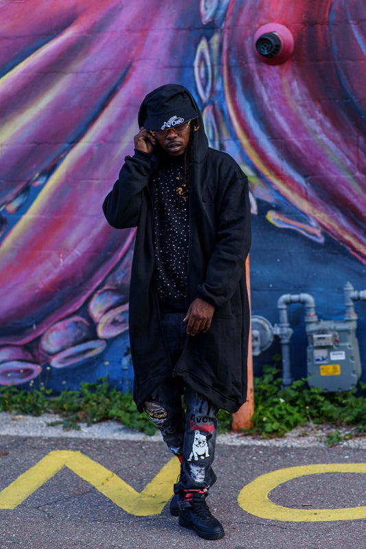 Man wearing the Marathon Hoodie | Avoir Fall Season against a colorful mural, showcasing streetwear style.